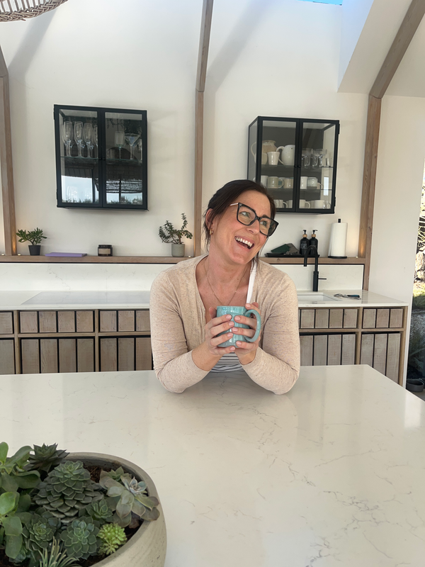 Elizabeth McGregor holding a handmade ceramic mug in a design-led kitchen with natural light — one of her filming locations